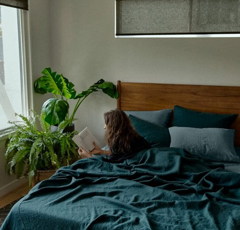 A girl reading comfortable on a bed with linen sheets