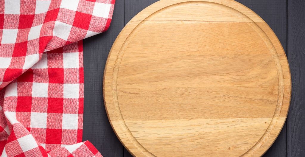 Round table with wooden cutting board and red & white checkered cloth